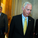 Senator Ron Johnson, a Wisconsin Republican, leaving the chamber. Senator Joe Manchin, a West Virginia Democrat, trails him on the left.